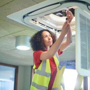 A woman looking at an air conditioning unit, fixing something