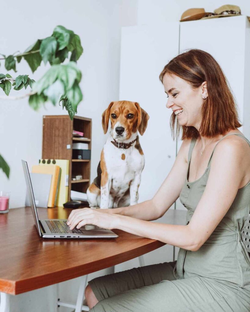A woman with her dog at home working as a hybrid worker
